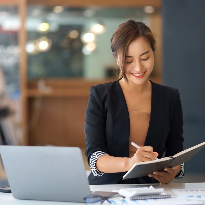 Professional taking notes during planning work on a computer